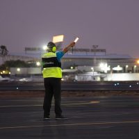 Ground handling staff guiding private aircraft landing using ramp signaling lights